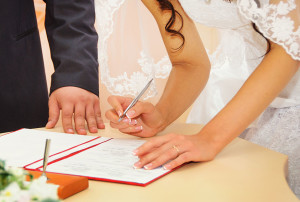 Ein Hochzeitspaar unterzeichnet die Hochzeitsurkunde beim Standesamt. 